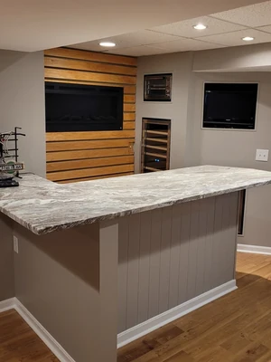 Finished basement remodel with custom bar, fireplace feature wall, and updated flooring by KNA Remodeling