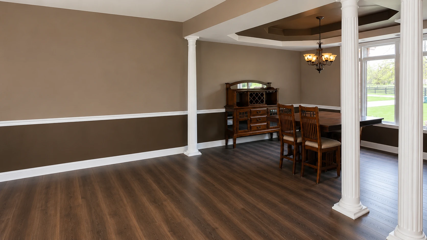 Interior remodeling with dark wood flooring, decorative columns, tray ceiling, and dining area by KNA Remodeling